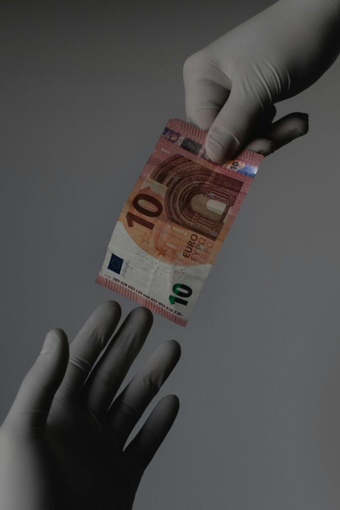 Sterile transaction concept with gloved hands exchanging a 10 Euro note.